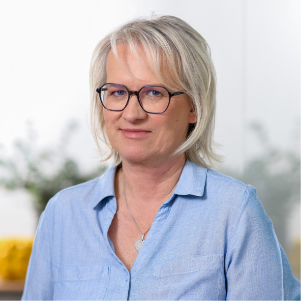 Porträt einer Mitarbeiterin in einer Steuerkanzlei mit Brille und blauem Hemd