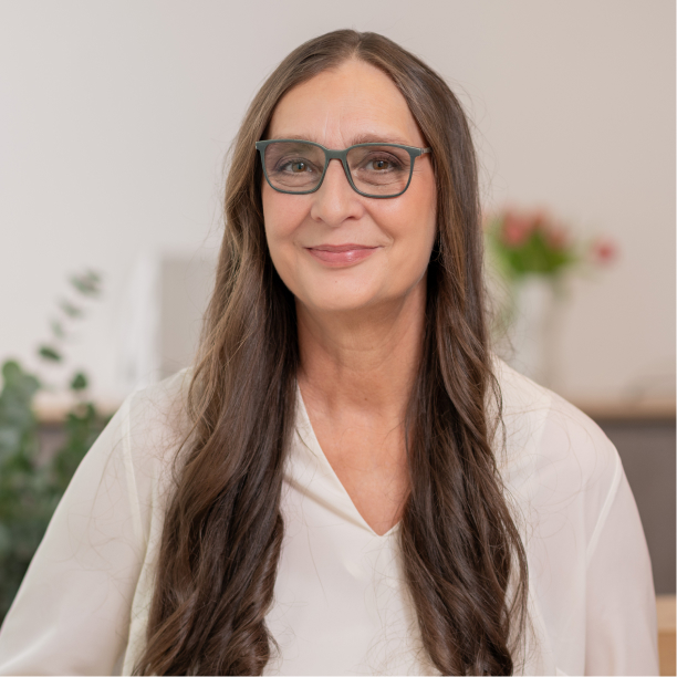 Porträt einer Mitarbeiterin mit Brille vor hellem Hintergrund